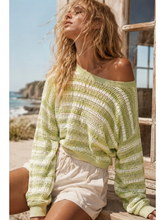 Load image into Gallery viewer, Woman wearing a light green sweater sitting by a window with a scenic view of the ocean.
