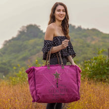 Load image into Gallery viewer, Woman holding a purple bag with a star design in a natural setting
