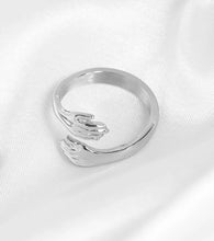 Load image into Gallery viewer, A silver-toned ring featuring two interlocking hands.
